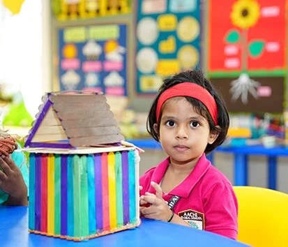Kindergarten student doing hands-on learning with a colorful craft model in class.