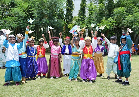 Students celebrating a cultural event outdoors in colorful traditional costumes with peers